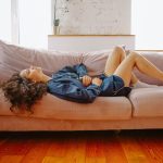 Mujer tumbada en el sofá de casa con una leve molestia abdominal