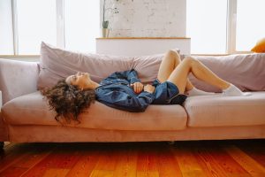 Mujer tumbada en el sofá de casa con una leve molestia abdominal